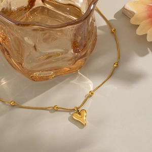 Detail of 18K gold plated heart pendant necklace featuring elegant golden beads