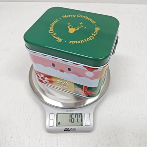 Detailed view of the Christmas tin box weight measurement showing its festive patterns