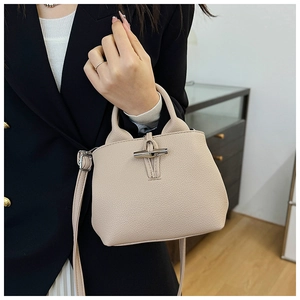 Detailed close-up of beige lychee texture leather bucket bag with bamboo clasp buckle