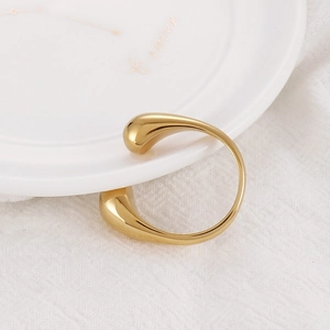 Detailed macro view of the gold teardrop open ring on a luxury ceramic surface
