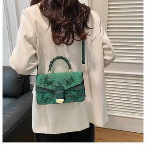 Détail de broderie de papillons et fleurs sur un sac à main vert foncé chic