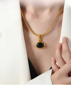 Close-up of gold snake bone chain necklace featuring a vintage oval black gemstone pendant
