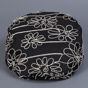 Close-up of white floral embroidery details on black cotton canvas newsboy cap