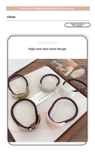 Detail of five handmade geometric acetate hair ties with marble texture and gold label