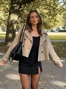 Women's khaki double-breasted short trench coat with black mini skirt and tote bag