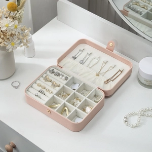 Pink PU leather jewelry organizer box with necklace hooks and ring slots on white table