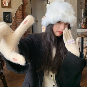 Close-up of beige knit gloves featuring pink cat paw pads and fabric labels for women