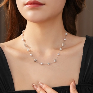 Detail of silver clover pendant necklace with pearls and zircons on model's neckline