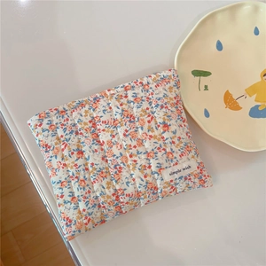 Detailed view of cream floral quilted cotton makeup bag with a vintage zipper closure