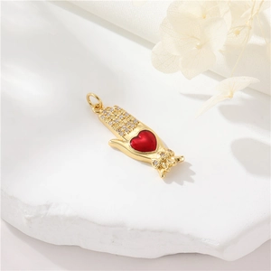 Golden hand holding red heart pendant with zircon accents on elegant white background