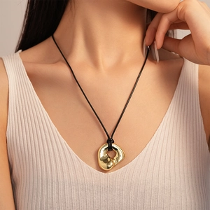 Minimalist gold irregular geometric necklace pendant on black cord worn by a model