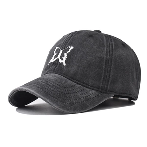 Detailed view of white butterfly embroidery on a black washed cotton baseball cap