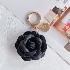 Detail of leather camellia keychain with golden coin pendant and spring buckle