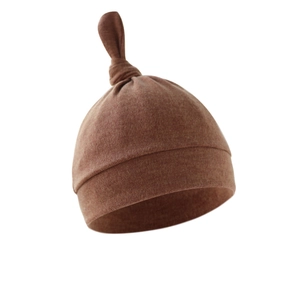 Close-up of brown knitted newborn baby hat with soft fabric and top knot detail