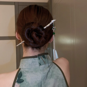 Detail of silver hair stick with green beads and long metallic tassels on model