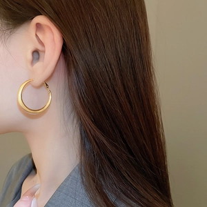 Close-up of minimalist gold plated metal hoop earring worn by a model in profile