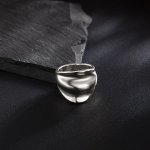 Macro shot of silver irregular metal ring featuring a streamlined vintage design on dark stone
