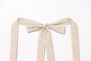 Close-up of beige and coffee plaid pattern on woven halter neck cotton dress fabric
