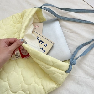 Detail of light yellow quilted tote bag with blue denim strap and large interior capacity