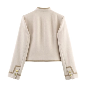 Blazer court beige avec épaulettes et poignets à boutons dorés sur fond blanc