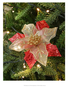 Detail of red and gold glitter poinsettia flower ornament on Christmas tree branch