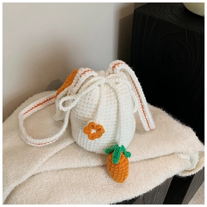 Close-up of handmade white crochet bucket bag with carrot charms and rabbit ear design