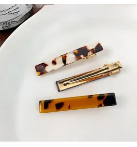 Close-up of tortoise shell acetate duckbill hair clips set on a white ceramic plate