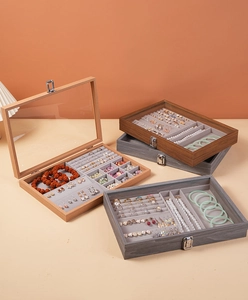Macro view of walnut jewelry box with transparent glass lid and soft grey velvet lining