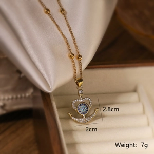 Macro shot of gold-plated evil eye anchor pendant with blue gems and dimensions 2.8cm by 2cm