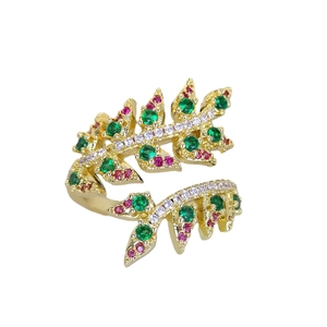 Luxury gold leaf ring with sparkling green and red zircon stones on a white background