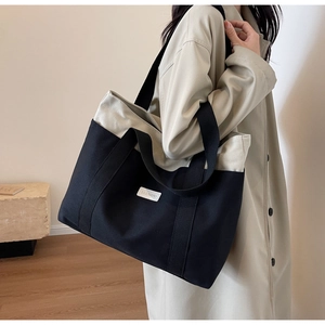 Canvas tote bag with black and white contrast stitching and spacious interior shown on shoulder