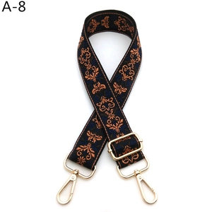 Close-up of vintage floral embroidery on adjustable bag strap with gold metal hooks