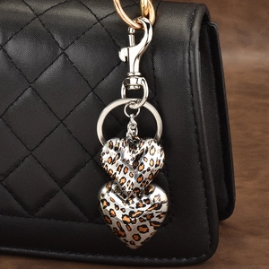Double-layered leopard print heart keychain with silver lobster clasp on black bag