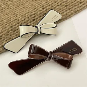 Detail of French bow hair clips in cream and dark coffee with glossy finish