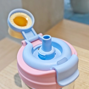 Close-up of pink and blue straw lid with yellow silicone seal on a clear plastic cup