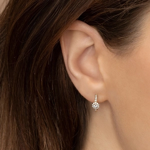 Close-up of golden hoop earrings featuring a flower design with sparkling white zircons