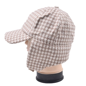 Side view of winter ear-flap baseball cap in classic brown and white houndstooth tweed
