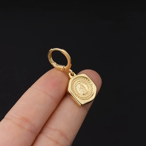 Detailed close-up of a gold-plated earring featuring a Virgin Mary religious pendant