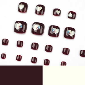 Glossy burgundy pedicure press-on nails with white heart patterns and tiny rhinestones