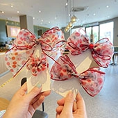 Detail of sweet cherry print bow hair clip with red sequins trim held in hand