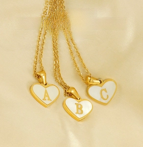 Detailed macro view of heart-shaped shell necklaces with gold initial letters A B and C