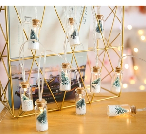 Close-up of LED wishing bottle string light with mini Christmas tree and artificial snow