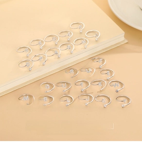 Detailed view of silver S925 alphabet rings with zircon stones on a beige notebook