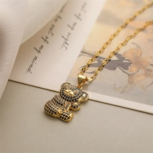 Detail of a gold bear pendant necklace encrusted with dark blue crystals on soft fabric