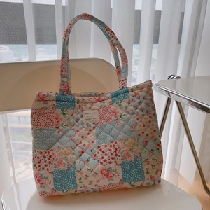 Quilted floral cotton tote bag with vintage patchwork design on a minimalist white chair