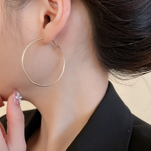 Gros plan de grandes créoles dorées élégantes portées par un mannequin pour un look chic
