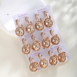 Detail of rose gold flower earrings with round zirconia on a white jewelry display card