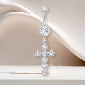 Gros plan d'un piercing de nombril en argent avec un pendentif croix serti de zircon