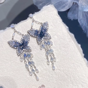 Makroaufnahme blauer Kristall-Schmetterlingsohrringe mit Silbernadel und eleganten Quasten
