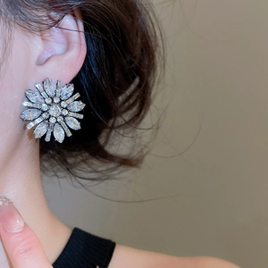 Macro view of crystal flower stud earrings featuring Marquise cut stones on a model